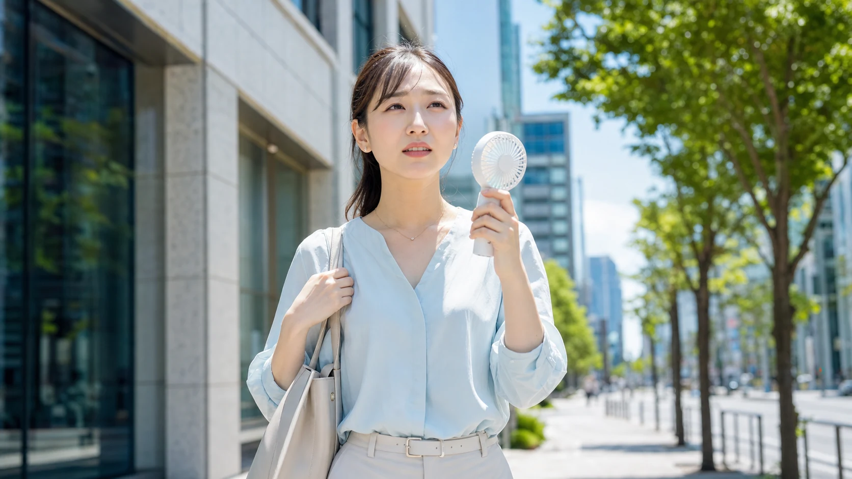 夏の屋外でハンディファンを使う女性
